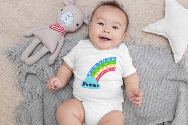 baby layin on blanket wearing a white onesie with a rainbow and word Nuanua on it